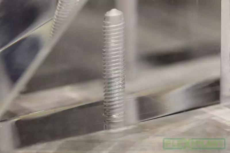Detailní záběr na řešení šroubu v plexiskla, robotická ruka